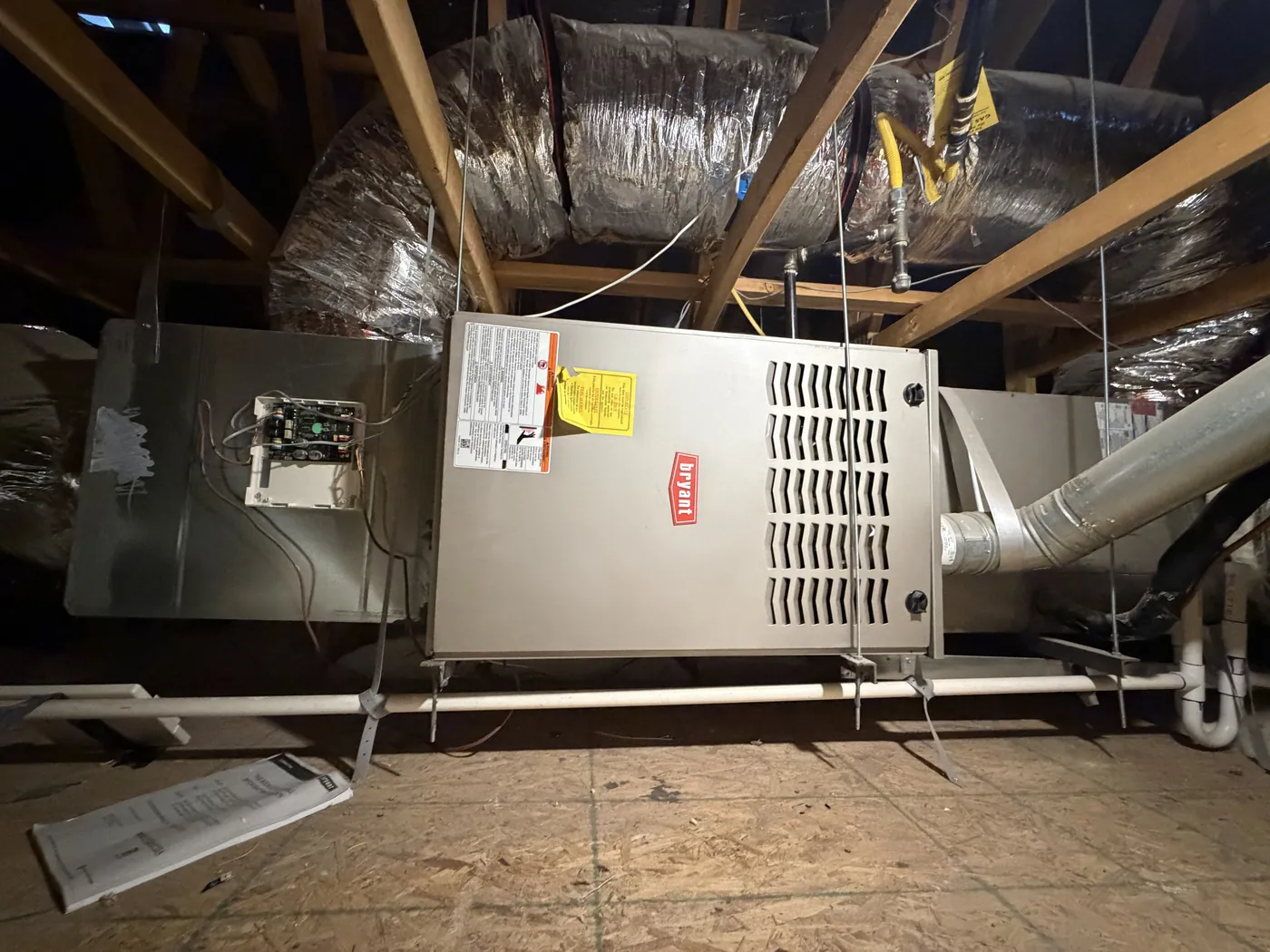 Gas furnace installed on a platform in an attic with ductwork above