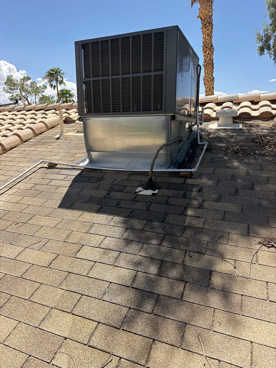Rooftop cooling unit on a metal curb over a tile roof