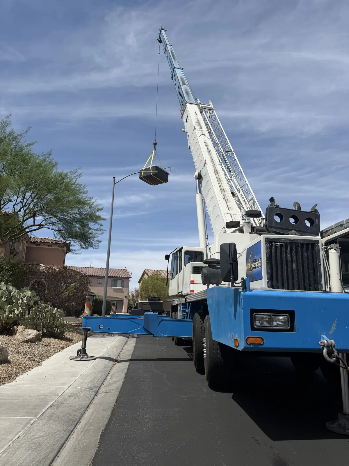 Crane lifting a heating and cooling unit into place on a residential street